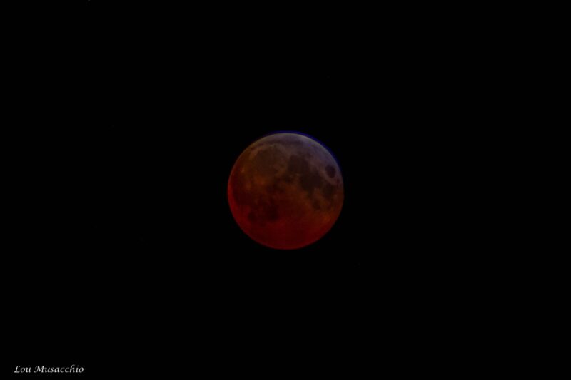 Dark moon that looks reddish at bottom, orangish in the middle and grayish at top.