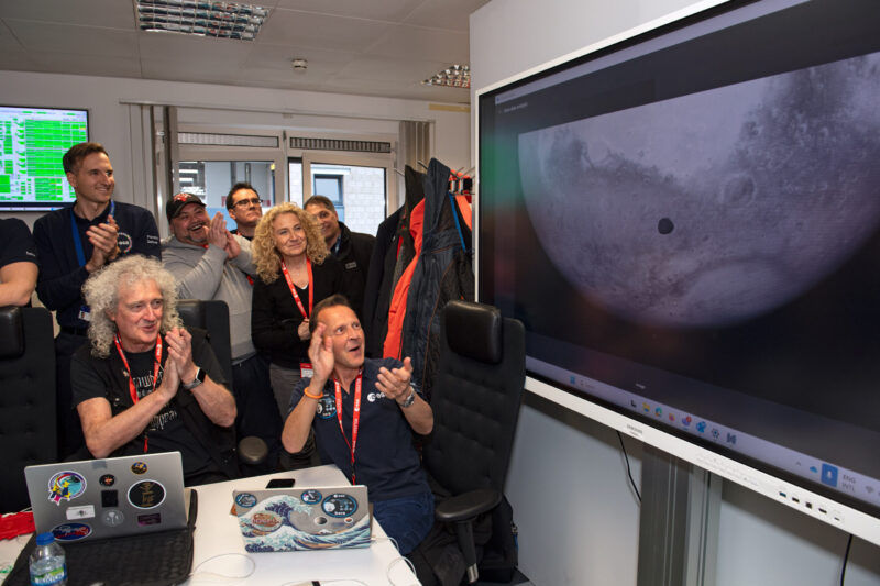 A group of people clapping as they look at a screen with Mars and a little moon.
