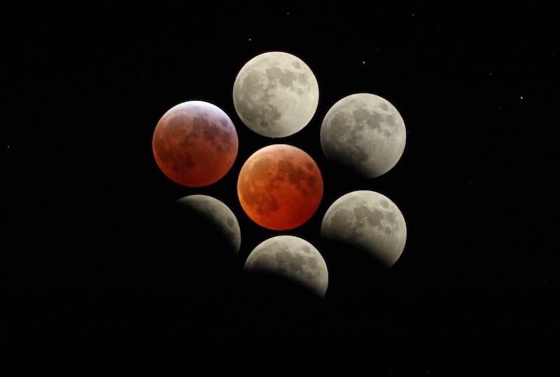 7 moons, some partly eclipsed and the one in the middle glowing orange.