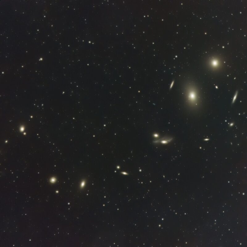 Two dozen yellowish nebulous patches with numerous foreground stars.