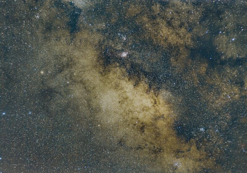 Dense field of stars with some brighter spots and dark paths.