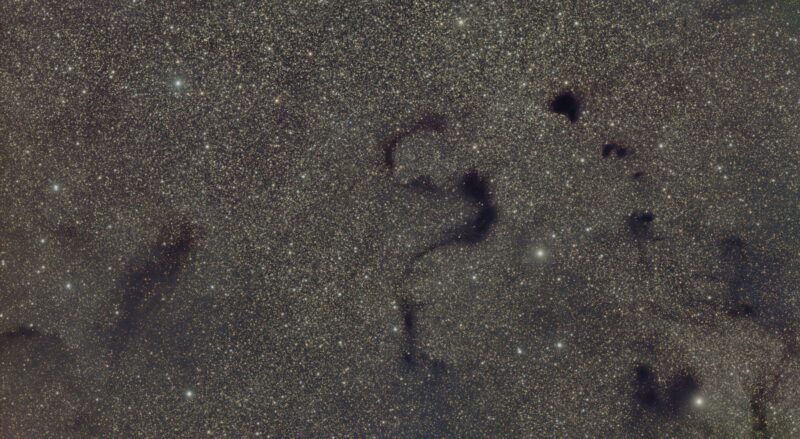 Star field with dark shape like an S blocking starlight behind.