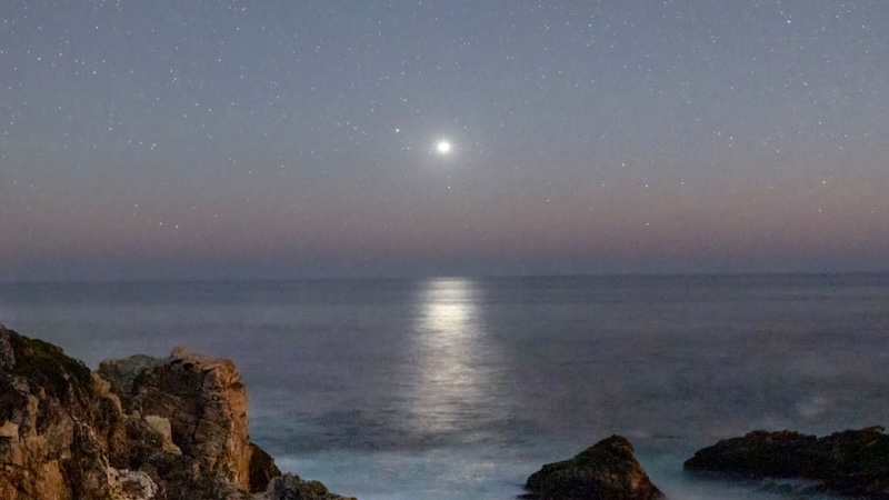 Venus shining brightly in dark twilight over the ocean.