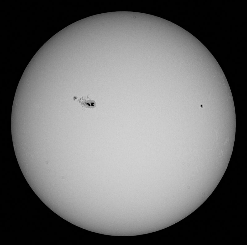 The sun, seen as a large white sphere with small dark spots.