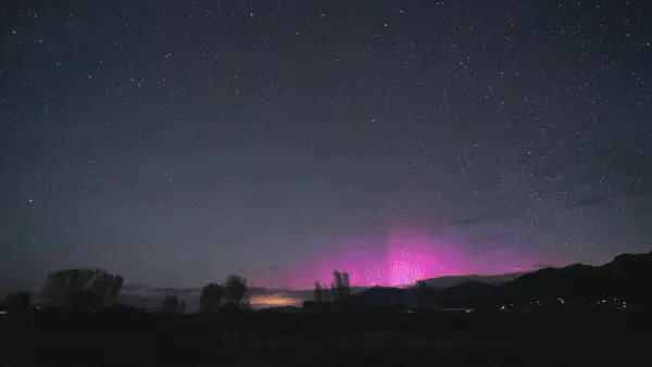 Pink aurora on the horizon and a big white streak moving from upper left to bottom center.