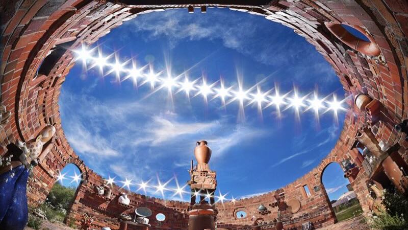 A round construction without roof. There are 2 lines made of images of the bright sun, one line is higher and larger.