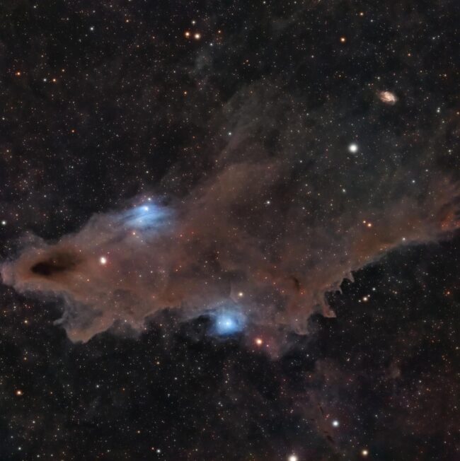 Large, dark pink nebulous complex with electric blue highlights, immersed stars and background stars.