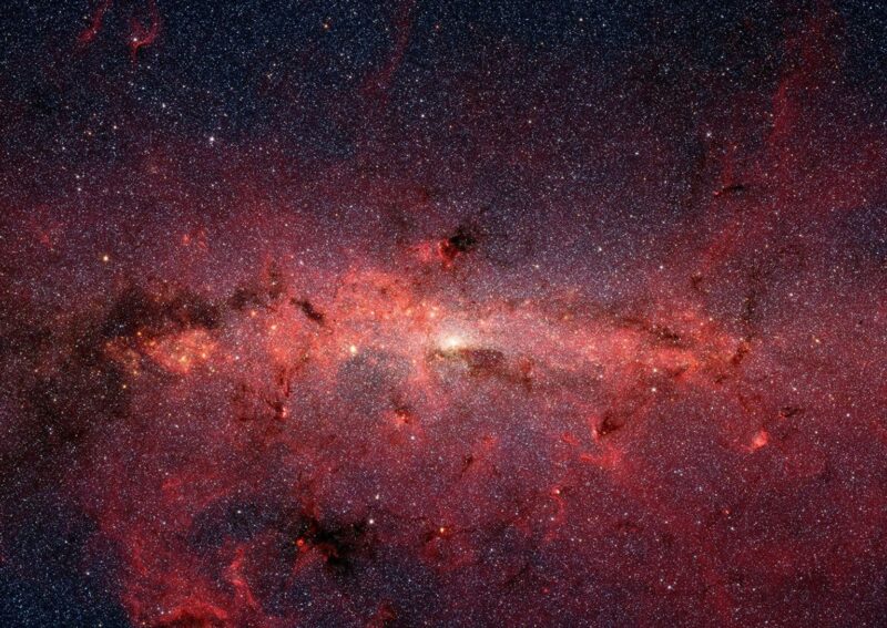 A whitish light near center with lots of stars around and red and dark-shaded clouds.