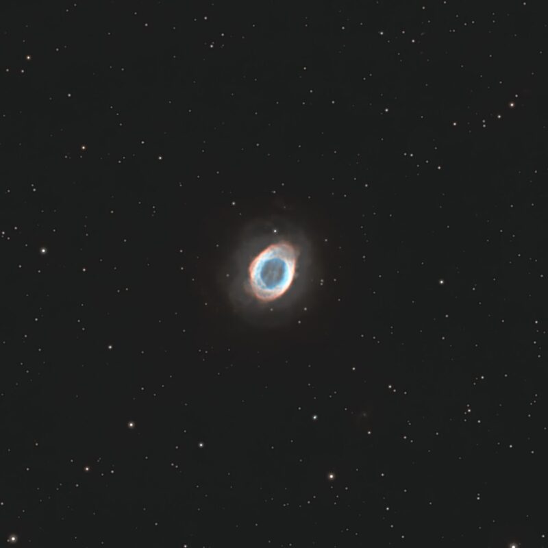 Small, ring-shaped cloud of gas in blue and orange, with sparse background stars.