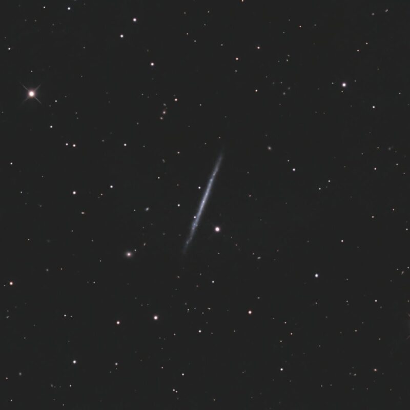 Thin cigar-shaped galaxy seen edge-on, with sparse foreground stars.