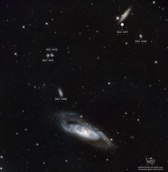 Bluish oval-shaped, a spiral seen edge-on, with a dark lane and foreground stars.