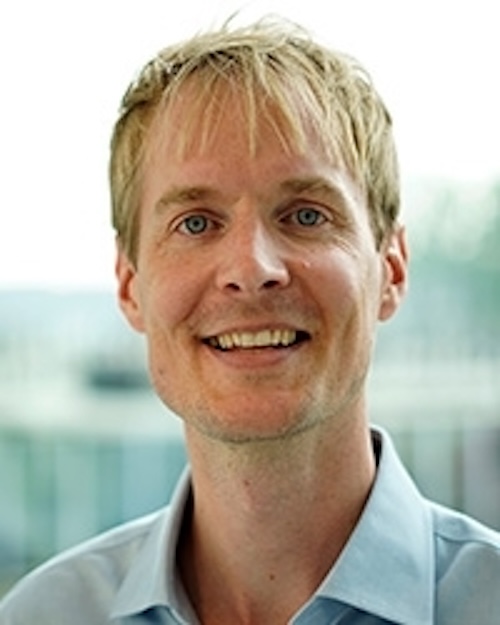 Smiling young man with bangs of blond hair.