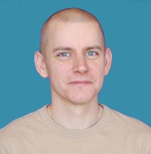 Smiling man with military-style short hair.