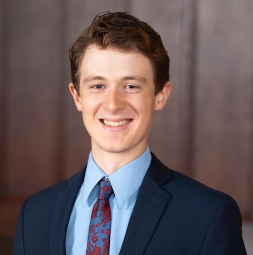 Young, smiling man in suit jacket and tie.