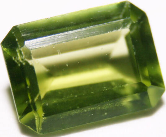 A green gemstone, cut into a rectangular shape with many facets.