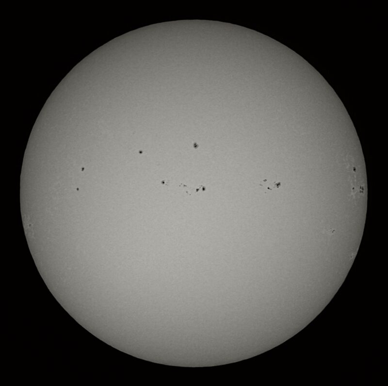 The sun, seen as a large white sphere with small dark spots.