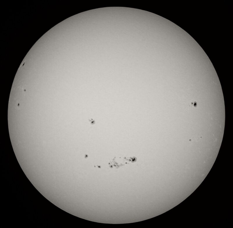 The sun, seen as a large white sphere with small dark spots.