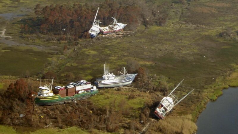 Aerial view of big boats including a small ship washed up on a green hillside.