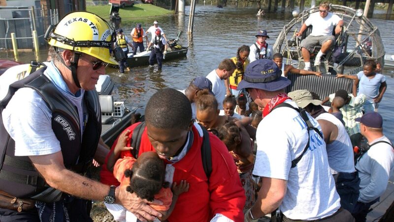 People being helped off a crowded fan boat, a man with a baby in the foreground.
