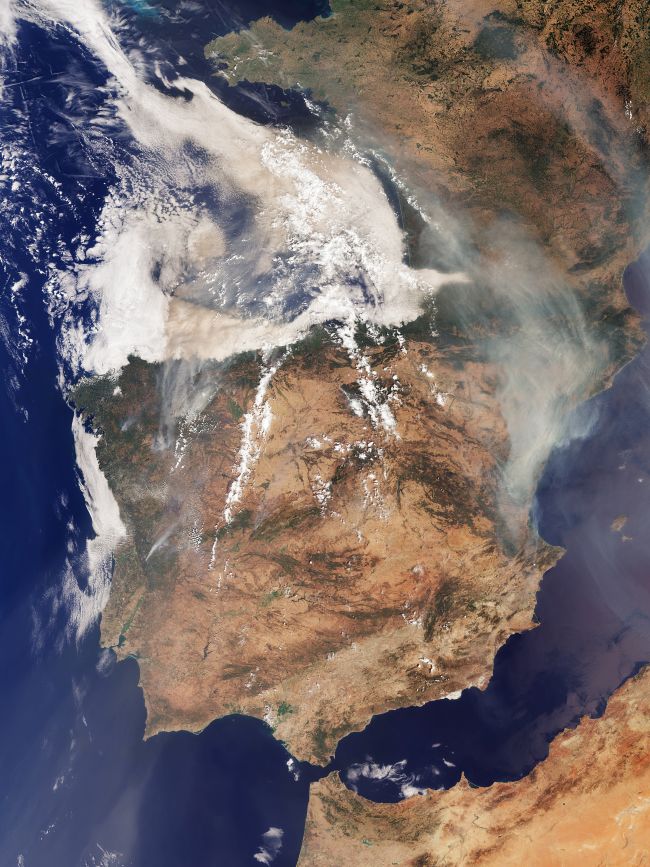 Iberian Peninsula wildfires: Satellite view looking at Spain, Portugal and France with long streamers of brown smoke coming from points in Spain.