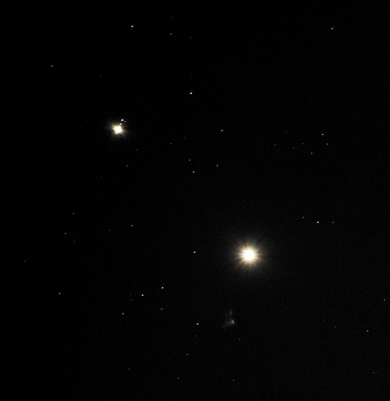 Dark sky with some stars and 2 bright objects. The one on the left side (Jupiter) has a line of dots crossing it.