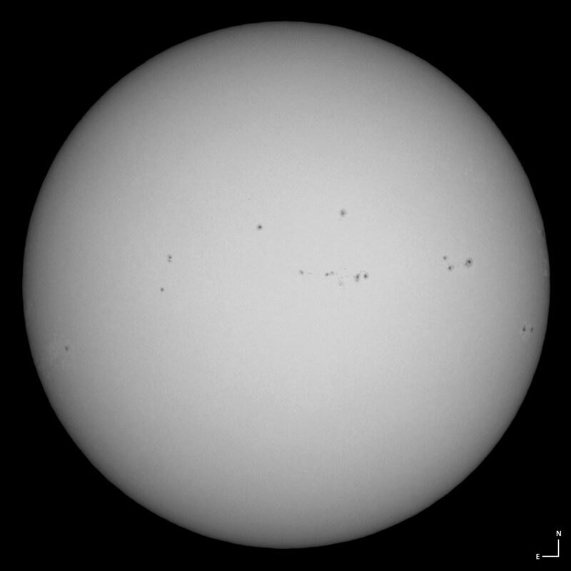 The sun, seen as a large white sphere with small dark spots.