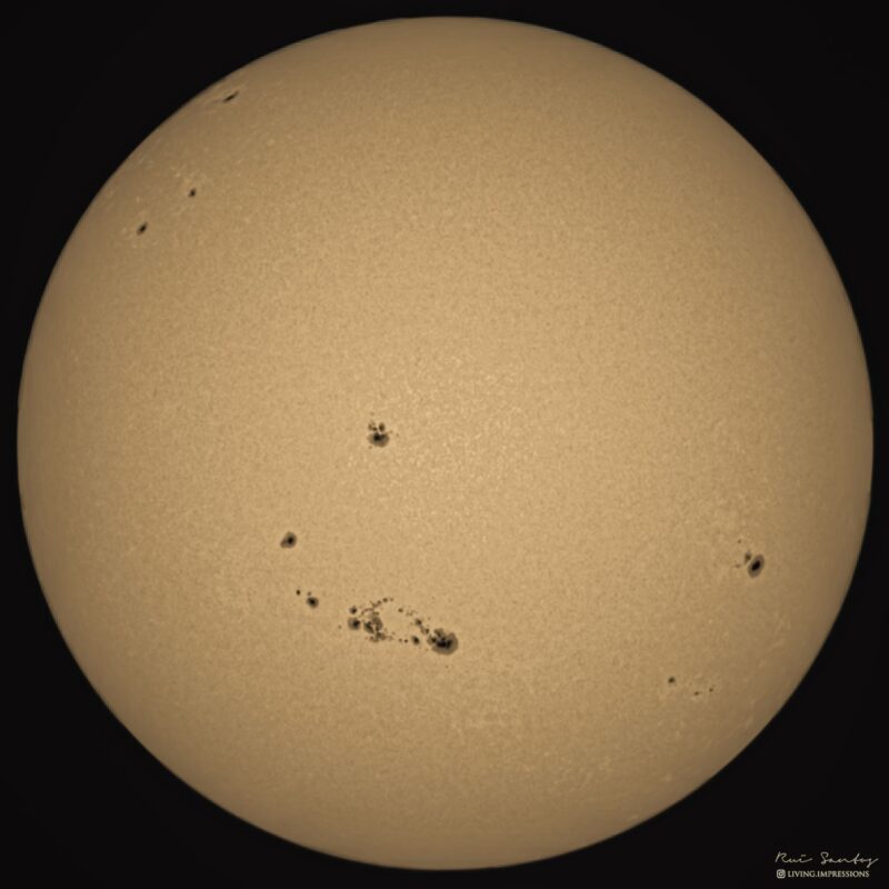 The sun, seen as a yellowish sphere with dark spots.