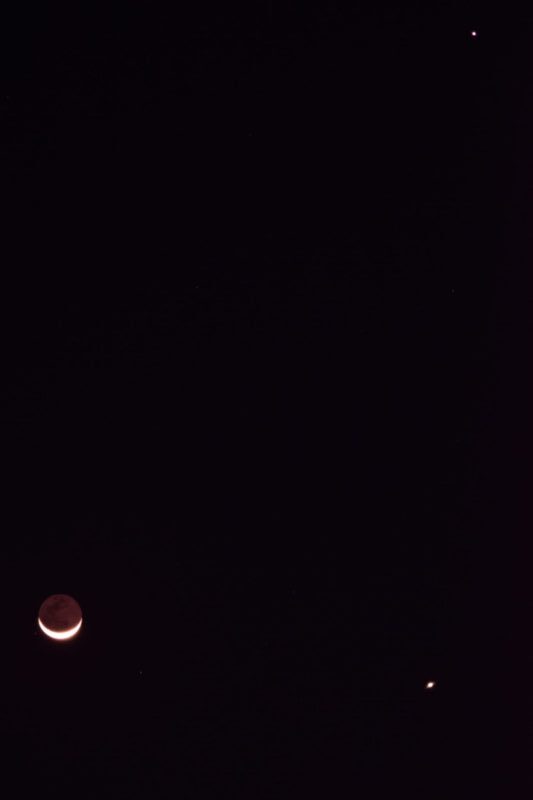 Black sky with the thin moon at the bottom left, Venus at the bottom right and Jupiter at the top right.