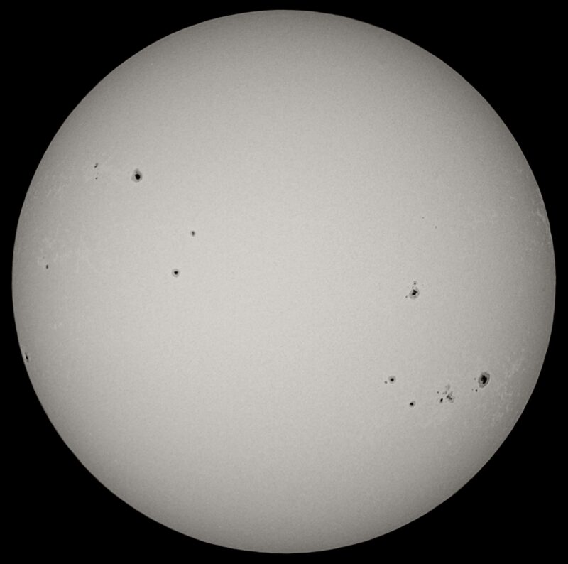 The sun, seen as a large white sphere with small dark spots.