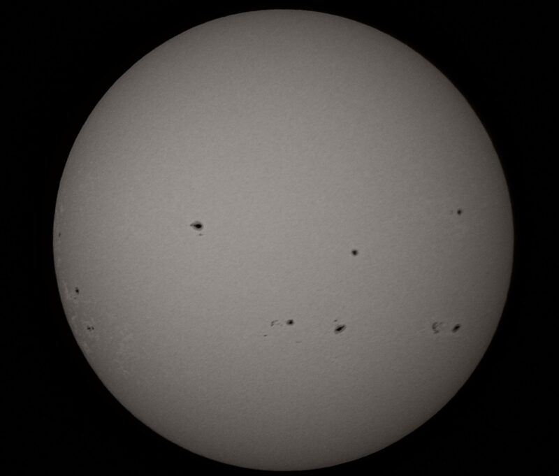 The sun, seen as a large white sphere with small dark spots.
