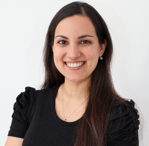 Smiling young woman with long dark hair wearing a black blouse.