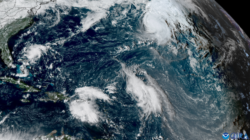 Satellite view showing 3 groups of white, dense clouds over the Atlantic.