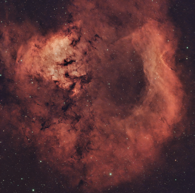 Large area of bright red gas surrounded by thousands of stars.