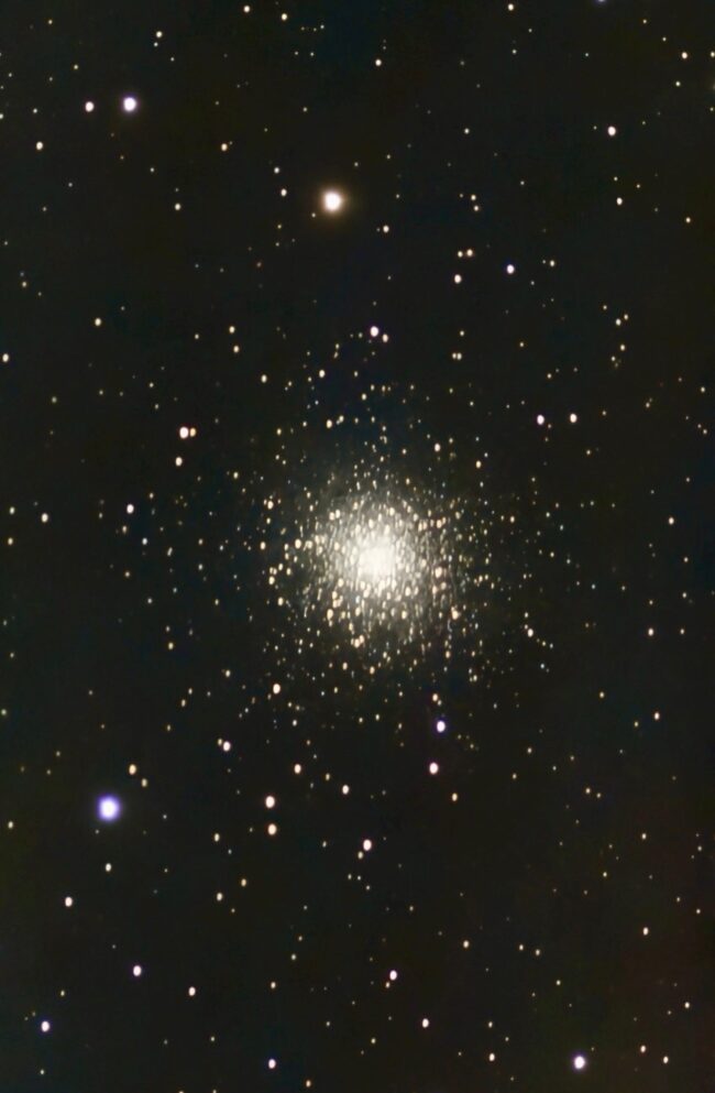 A large, spherical cluster containing thousands of bright yellowish stars.