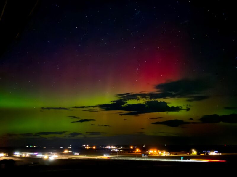 Green and pinkish lights over a small town at night.