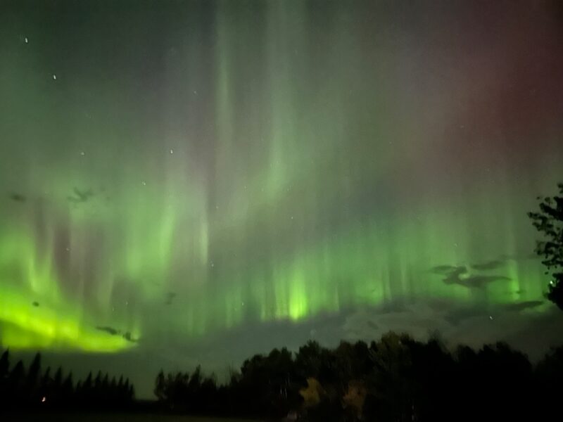 Green pillars of light and trees below.