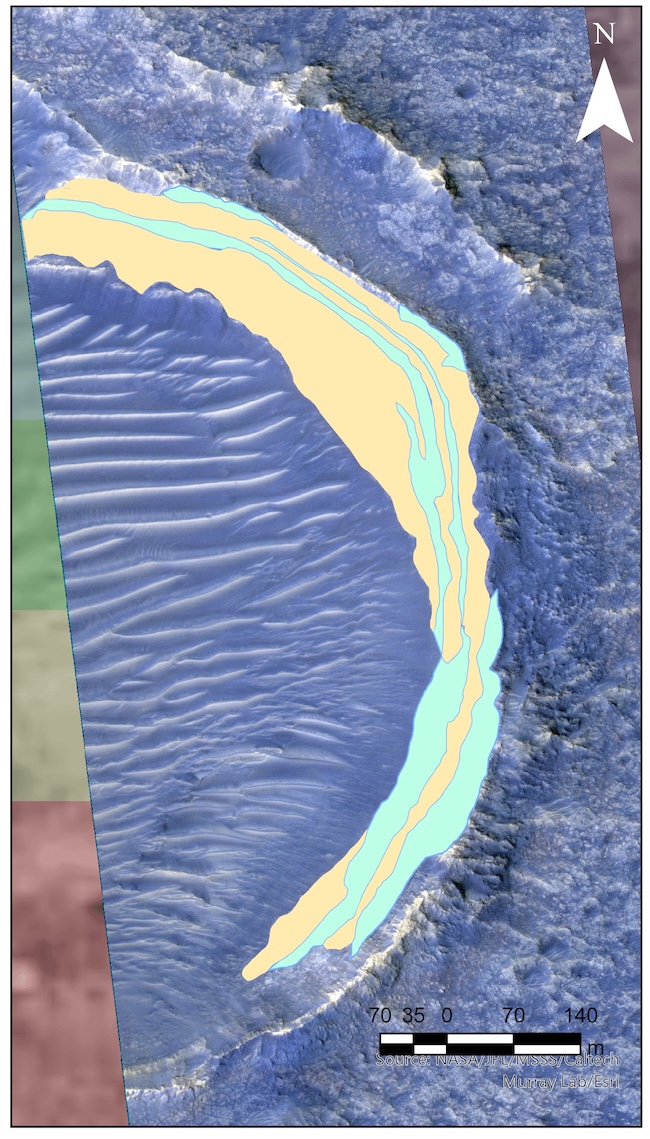 View from above of part of the edge of a crater. Long blue and yellow areas lie along the edge of the crater and sand dunes are on the crater floor.