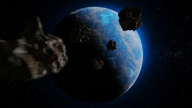 Asteroid impact: Artist's concept of a planet in space with blue water and pieces of an asteroid zooming toward it.