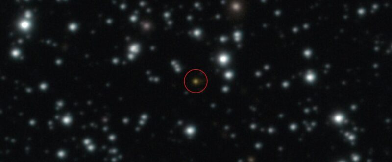 Gamma-ray burst: Black field with white blurry dots and a faint reddish point near center circled.