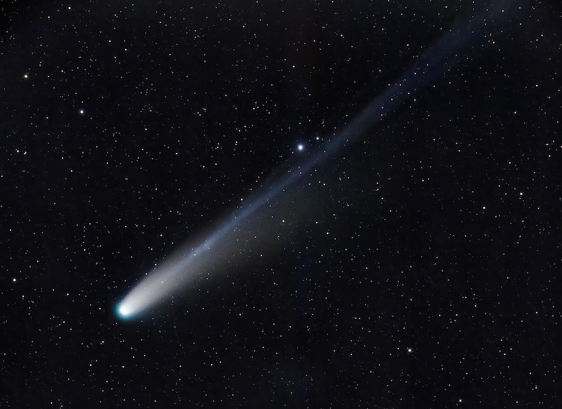 Bright comet with a long tail against a starry sky.