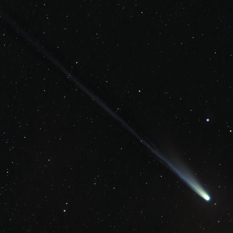A comet with a long, narrow but diffuse tail stretching to the upper left.