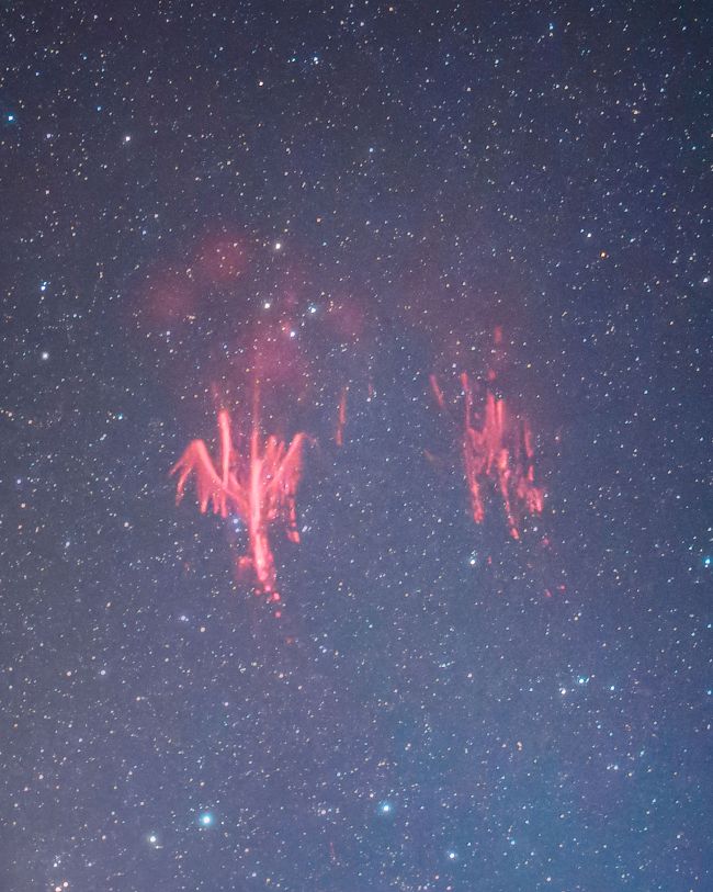 A starry background with 2 batches of vertical bright red streaks. One group looks a bit like a bird.