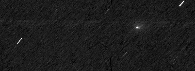 Black rectangle with streaks of white stars and a fuzzy white dot.
