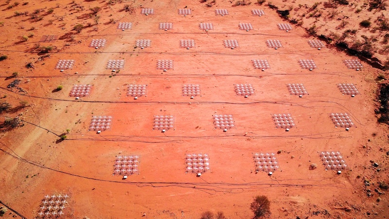 Aerial view of an orange-brown desert ground with square metallic structures next to each other.