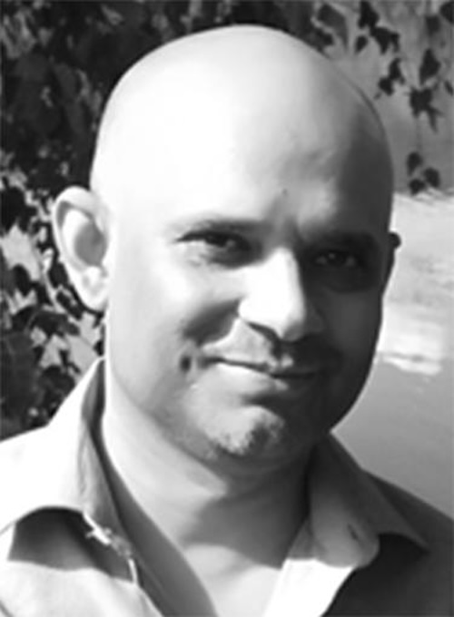 Black and white photo of a smiling bald man.