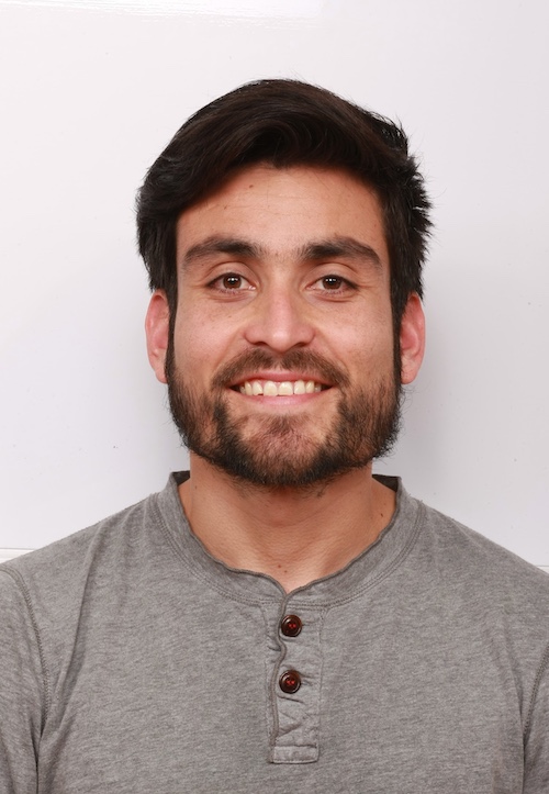 Smiling man with dark hair, beard and moustache, wearing a gray shirt.