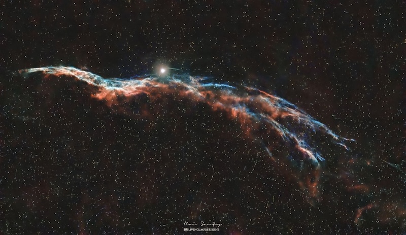 Протоци плаве и наранџасте маглине налик на старомодну метлу на звезданом небу са сјајном звездом изнад.