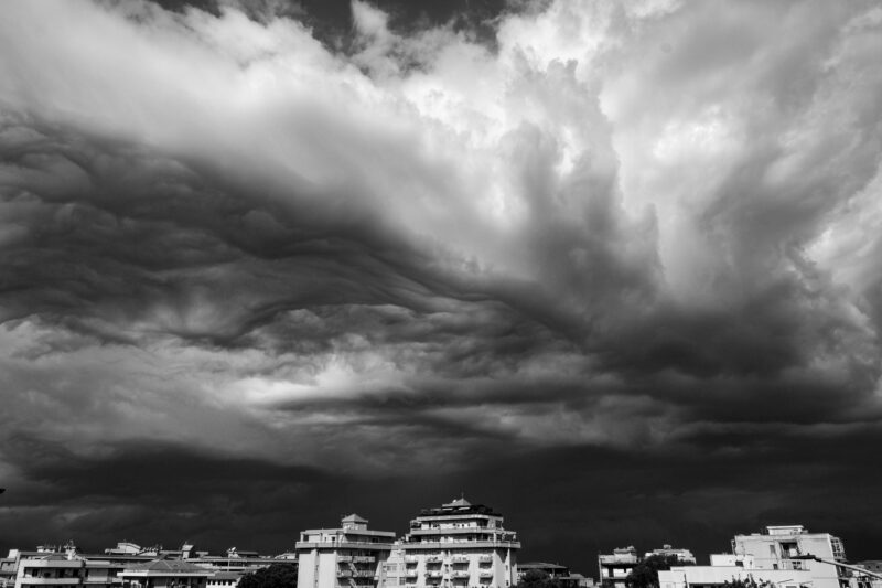 Dramatic black-and-white clouds from below and a couple building at bottom.