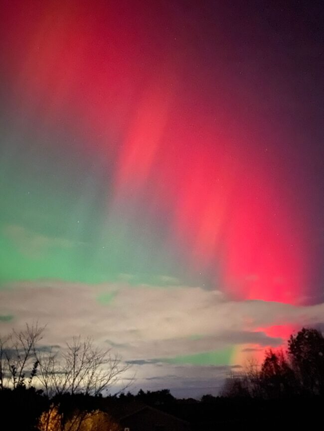 Clouds near the horizon, then green and then pinkish red extending nearly overhead.
