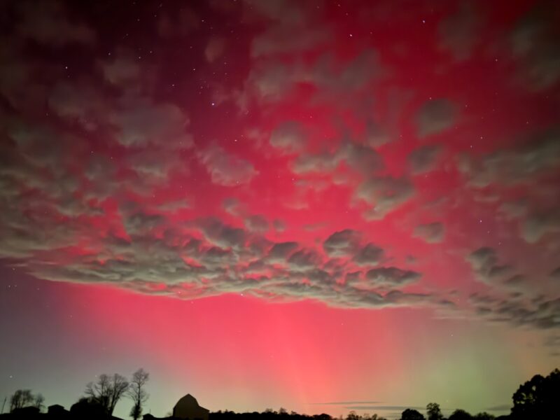A few thin clouds in the sky. Pink/red pillars of light break through and are visible in all the sky.